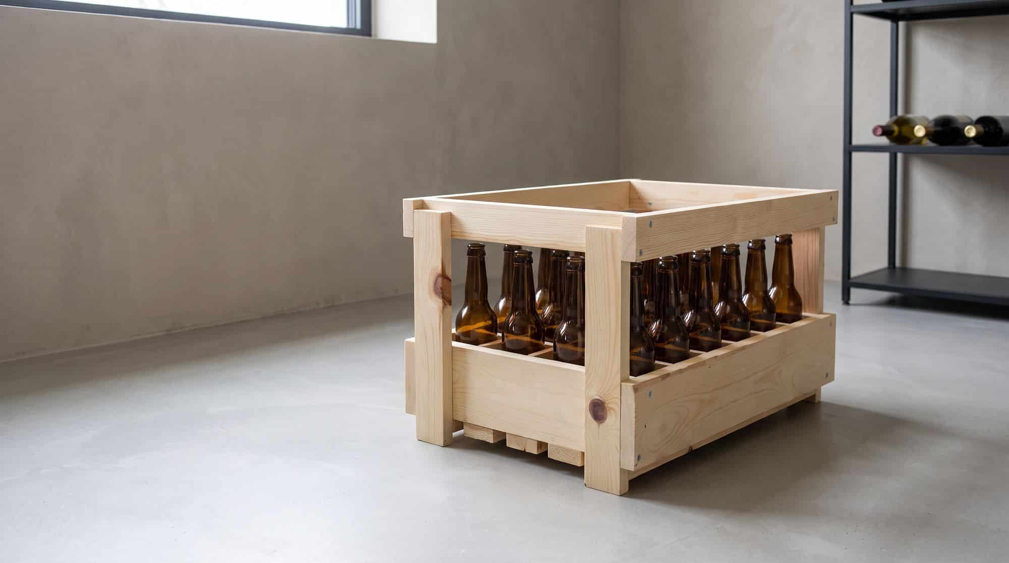 Casier à bière en bois rempli de 24 bouteilles long neck de 33 cl, dans une cave au sol de béton poli